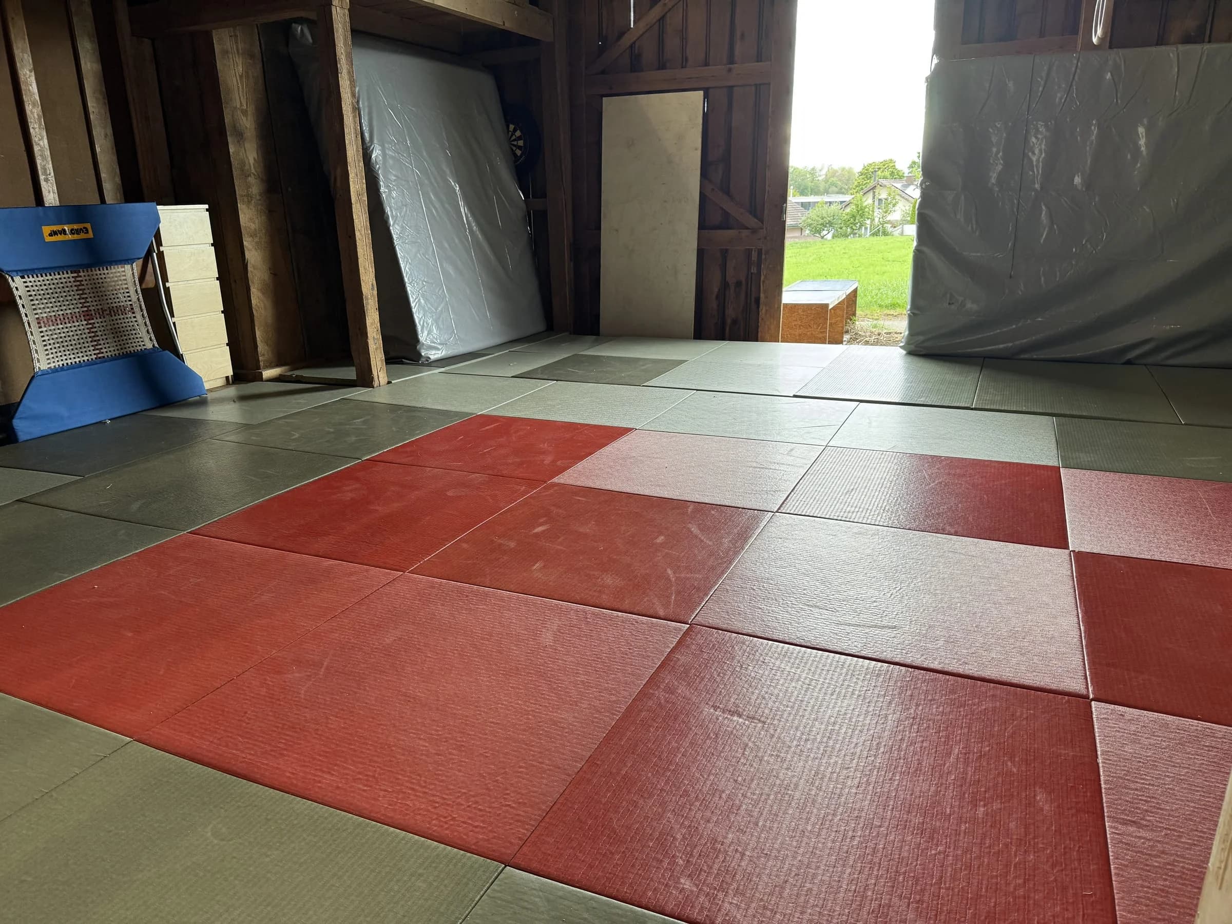 Rot-graue Mattenfläche im Dojo der Turn-Scheune, im Hintergrund das offene Tor
